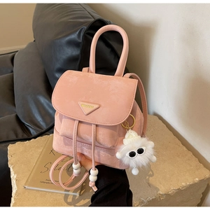 Detail of pink suede backpack with metal logo and cute plush eyeball charm accessory