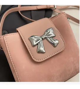 Close-up of pink mini bucket bag featuring a silver metal bow and fine matte texture