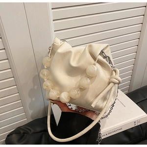 Macro view of creamy white cloud bag featuring large pearl handle and soft leather texture