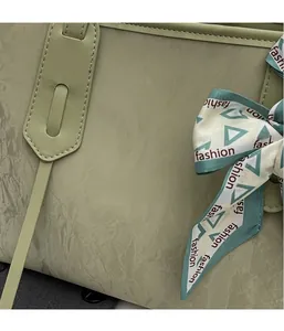 Detail of sage green tote bag showing wrinkled leather texture and fashion print scarf