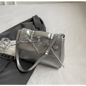 Gros plan d'un sac bandoulière argenté plissé avec nœuds décoratifs et fini métallisé