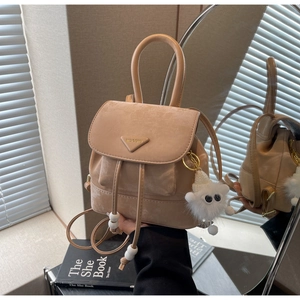 Detail of beige suede backpack with flap drawstring closure and plush lamb pendant
