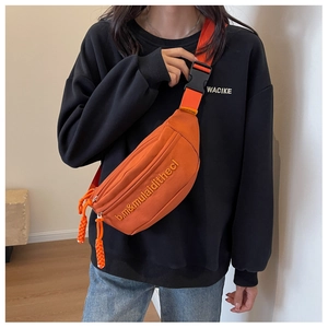 Detail of bright orange canvas crossbody bag featuring adjustable strap and buckle closure