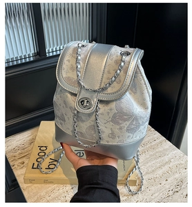 Close-up of silver backpack featuring butterfly patterns and metallic chain strap