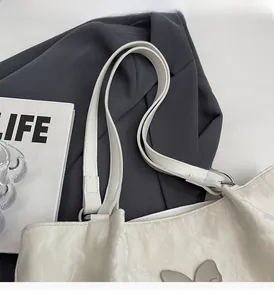 Detail of white butterfly tote bag showing glossy wrinkled leather and rabbit ornament