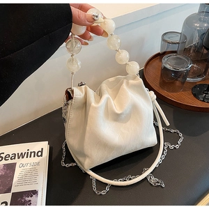Detail of white ruched bucket bag with oversized frosted clear beaded handle and chain