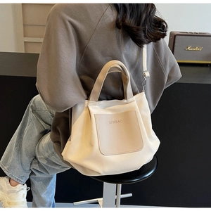 Vue arrière d'un mannequin portant un sac cabas en nylon crème avec détails en cuir