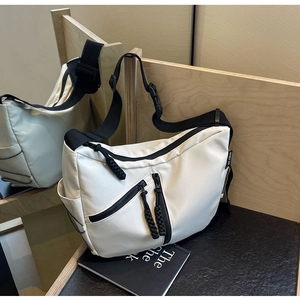 Detailansicht der weißen Nylon-Umhängetasche mit mehreren Taschen und schwarzen Gurten