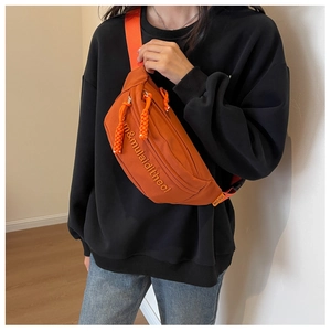 Detail of orange canvas chest bag featuring MULAIDI logo and textured braided zipper pull