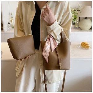Detailed view of brown lychee grain leather bucket bag with silk scarf and gold lock