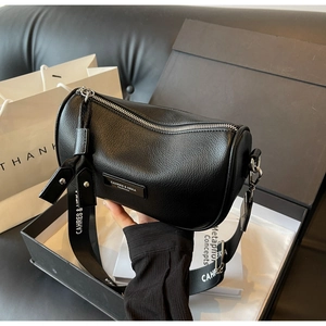 Close-up of black lychee grain pillow bag with wide jacquard strap in a gift box