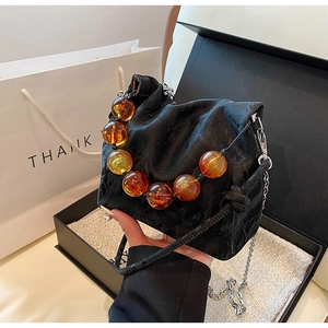 Detail of black cloud pleated handbag with amber bead handle and silver chain strap
