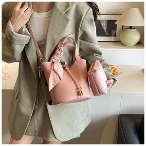 Detail of pink lychee leather bucket bag with silk scarf handle and small pouch charm
