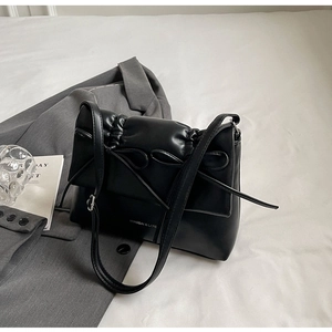 Détail du sac à bandoulière en cuir plissé noir avec deux nœuds décoratifs élégants