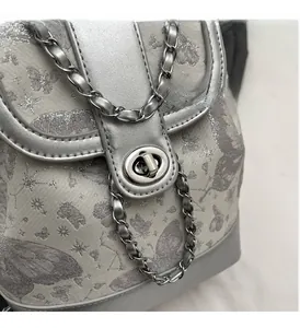 Detailed view of silver butterfly pattern bag with metallic twist lock and chain strap