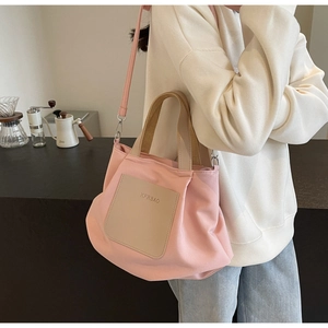 Sac fourre-tout en nylon rose avec poche cuir beige et bandoulière porté par mannequin