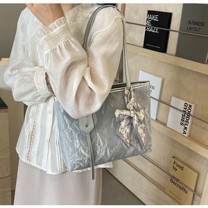 Close-up of silver-gray pleated tote bag with printed ribbon bow and metallic texture