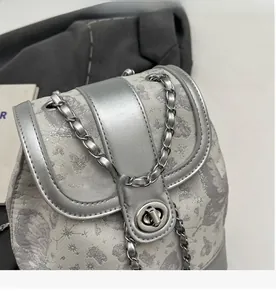 Close-up of silver-gray jacquard mini backpack with butterfly pattern and metal chain