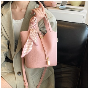 Detail of pink pebbled leather bucket bag with silk scarf handle and gold lock charm