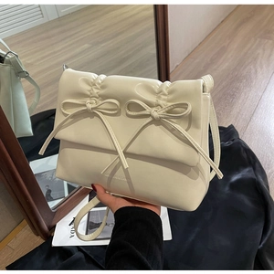 Détail d'un sac à bandoulière plissé beige avec double nœud et texture en similicuir lisse