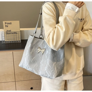 Chic grey tote bag with pleated texture and silver butterfly pendant on shoulder strap