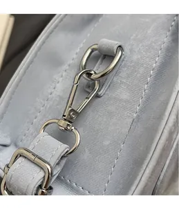 Detail of silver metal hook and neat stitching on light blue leather shoulder bag strap