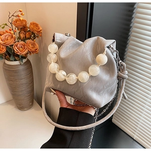 Detail of beaded handle and textured grey leather on a bucket bag with drawstring closure
