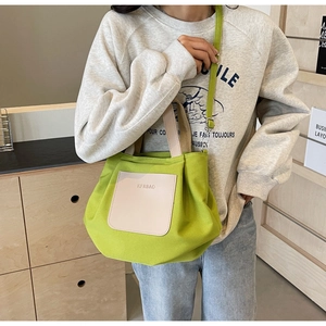 Détail du sac cabas en nylon vert avec une poche beige à l'avant et une bandoulière réglable