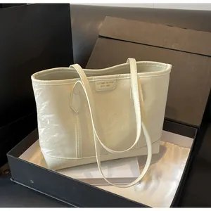 Close-up of a cream pleated tote bag with a vintage leather brand label in a black gift box