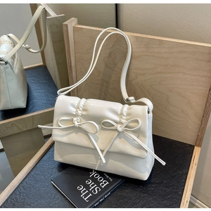 Détail d'un sac à bandoulière crème avec plis, nœuds décoratifs et logo embossé