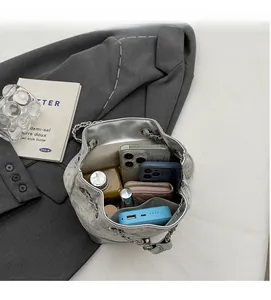Spacious interior of silver mirror bucket bag showing phones, power bank, and cosmetics