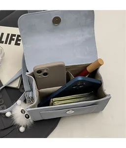 Detail of light blue satchel showing magnetic clasp and multi-layer inner compartment