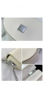 Detail view of cream saddle bag featuring silver hardware, chain strap and fine stitching