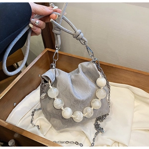 Detail of grey pleated cloud bag with marble bead strap and silver chain on silk