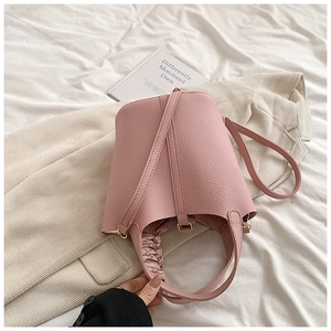 Detail of pink lychee leather bucket bag with elegant silk scarf handle and gold hardware