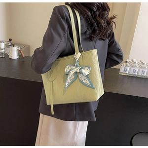 Detailed close-up of light green pleated leather tote bag with a decorative fashion scarf