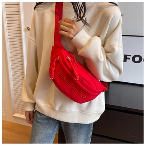 Detail of red canvas crossbody bag with letter embroidery and adjustable wide strap