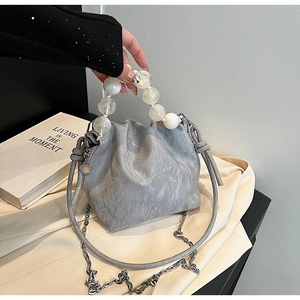 Detailed view of light gray bucket bag featuring pearl handle and pleated PU texture