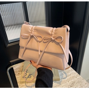 Détail du sac bandoulière plissé rose avec deux grands nœuds et logo de marque gravé