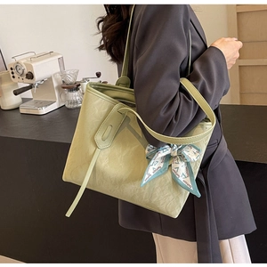 Detail of light green tote bag with pleated texture and stylish blue lettered silk scarf