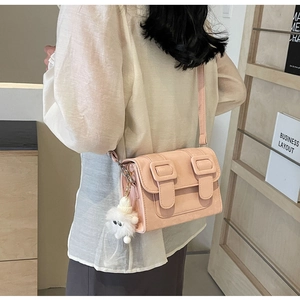 Close-up of a pink crossbody bag with a plush sheep charm in a minimalist interior