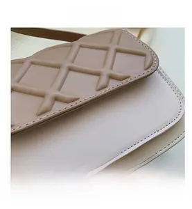 Gros plan sur la texture matelassée beige avec logo doré pour petit sac bandoulière
