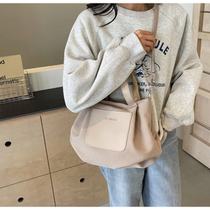 Détail du grand sac cabas en nylon montrant la poche avant en cuir et le logo épuré