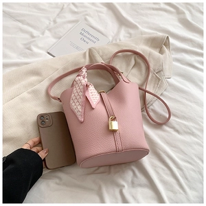 Detail of pink lychee leather bucket bag with silk scarf handle and golden lock clasp