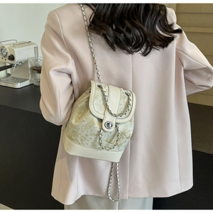 Detail of cream mini bucket bag with gold butterfly prints and silver chain straps