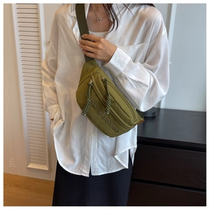 Close-up of olive green canvas crossbody bag with embossed letters and orange logo tag