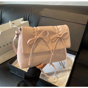 Gros plan d'un sac bandoulière plissé rose avec des nœuds décoratifs en cuir premium