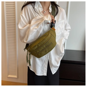 Close-up of army green crossbody bag with textured embossing and orange woven label