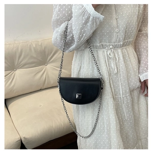 Detailed close-up of a black mini saddle bag with silver chain and metal buckle