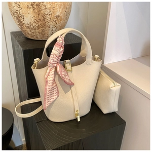Creamy leather bucket bag detail with pink silk scarf handle and gold hardware lock